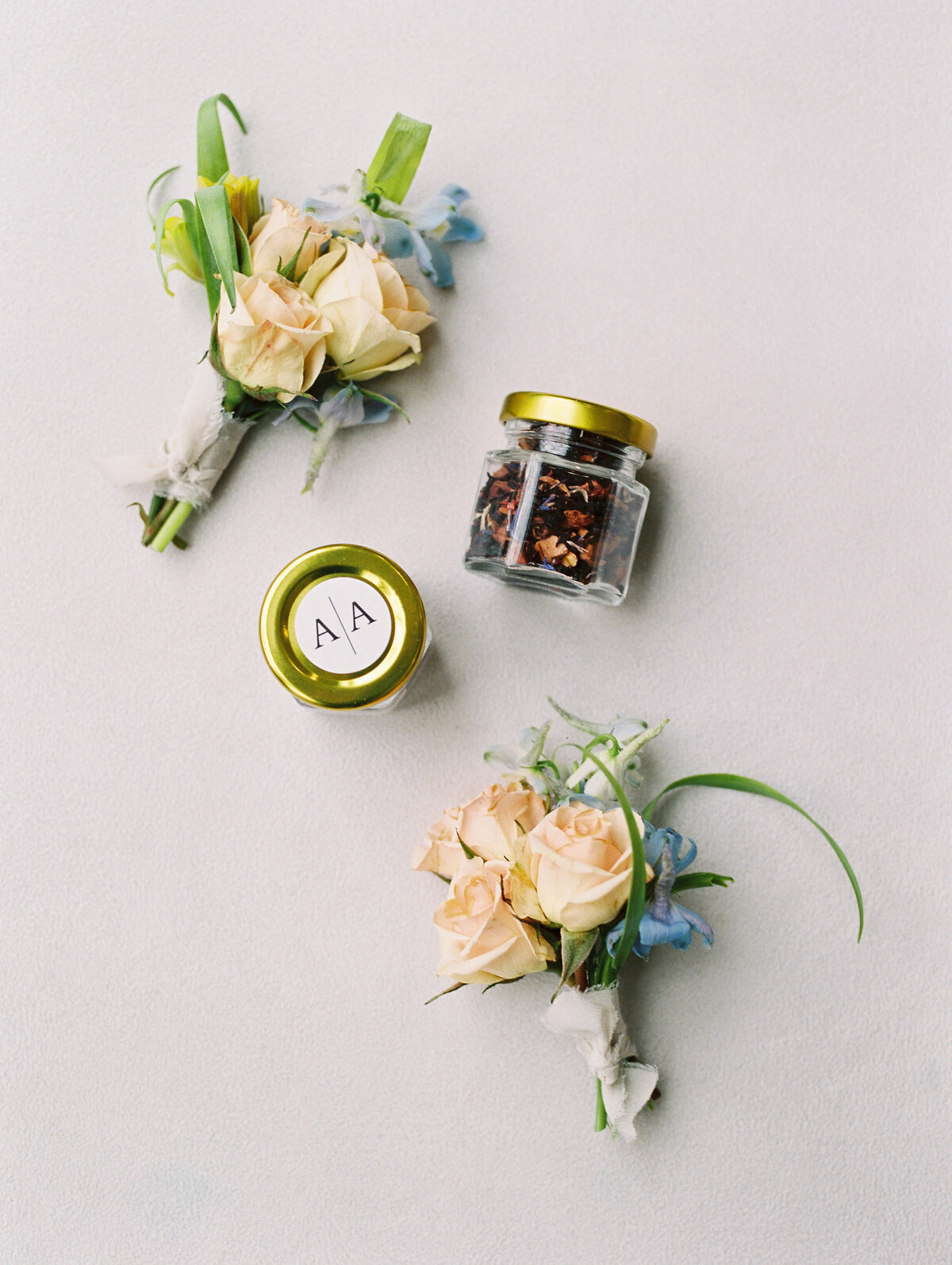 Two wedding boutonnieres on a flatlay with two wedding