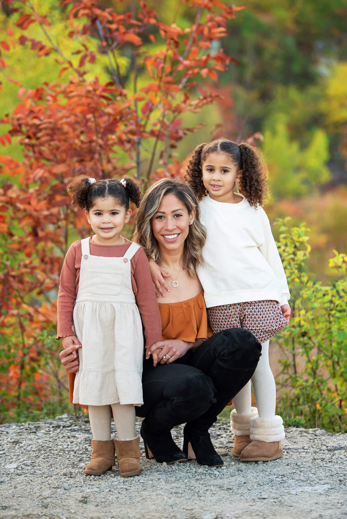 mom crouching down with her two daughter for their fall family photos