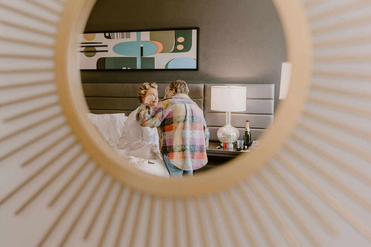 storyteller-collective-photo-co-bride-getting-makeup-done-through-mirror-hotel-rewind-west-des-moines-iowa