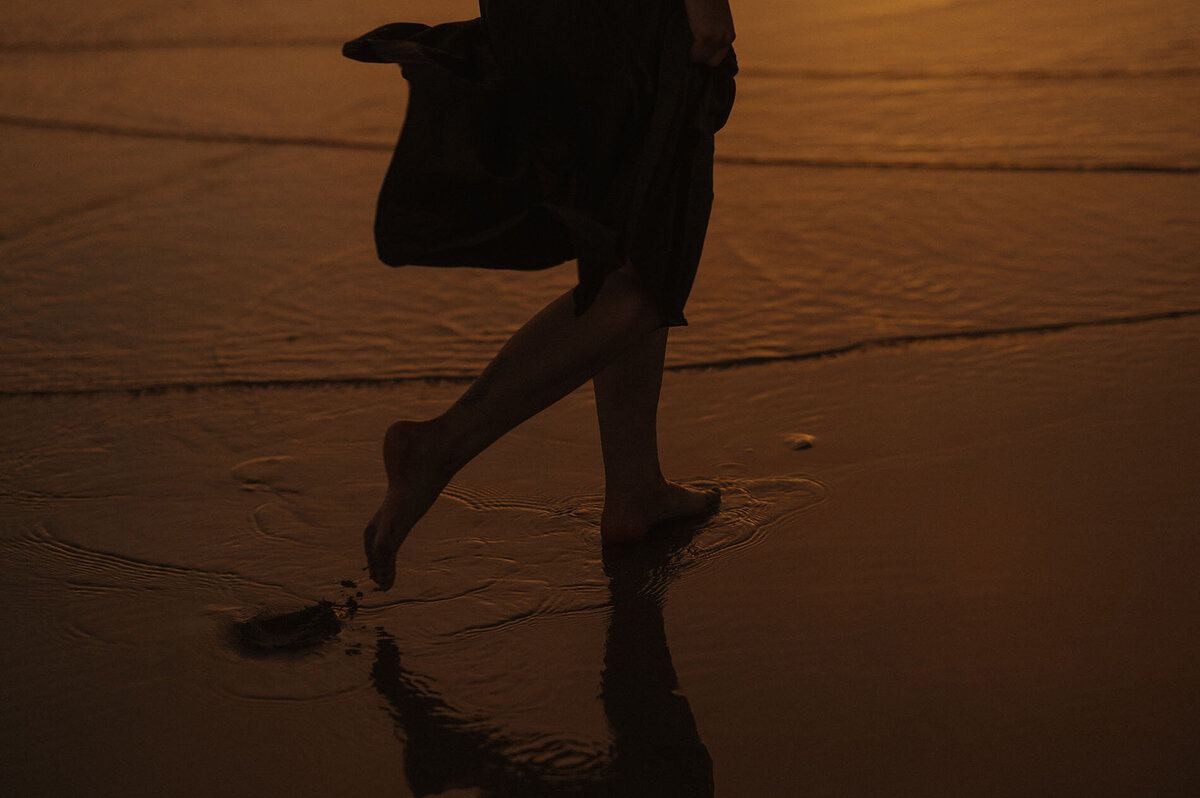 silhouette photo of a woman's legs and feet running along the Oregon coast shoreline during sunset