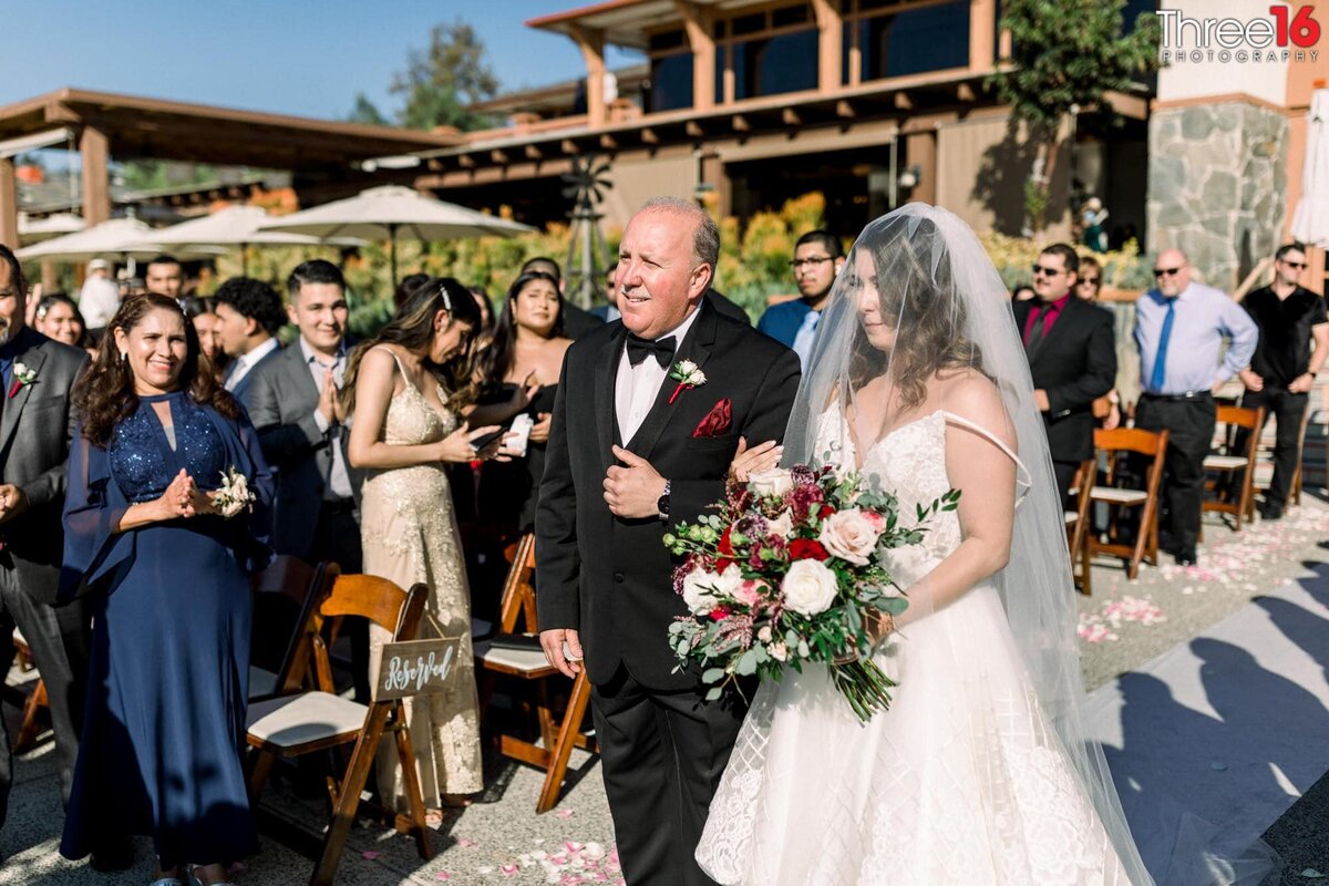 Bride being escorted by her father up the aisle towards the waiting Groom at the altar