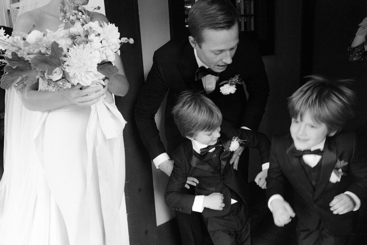 Two happy, little boys are with the bride and the groom in Foxfire Mountain House, New York. Wedding Image by Jenny Fu Studio