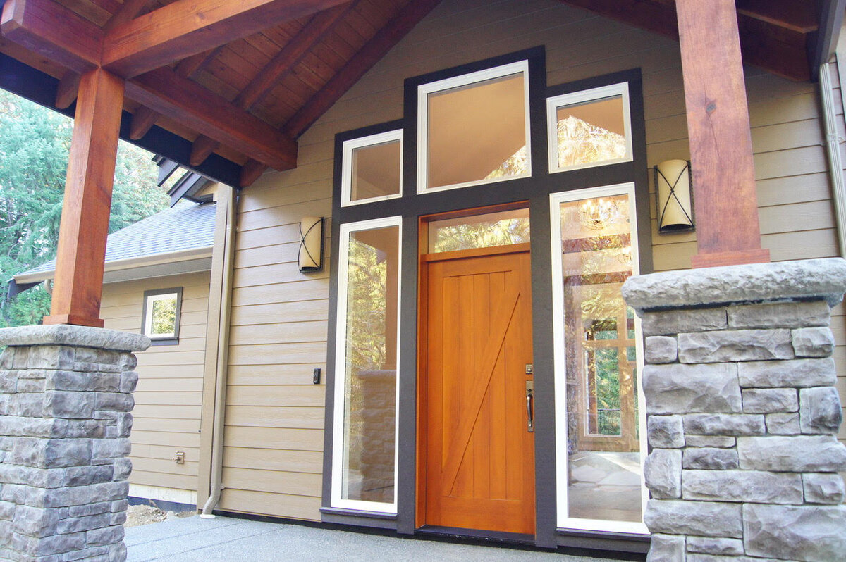 Craftsman home design exterior entryway with stone pillars and wood beams.