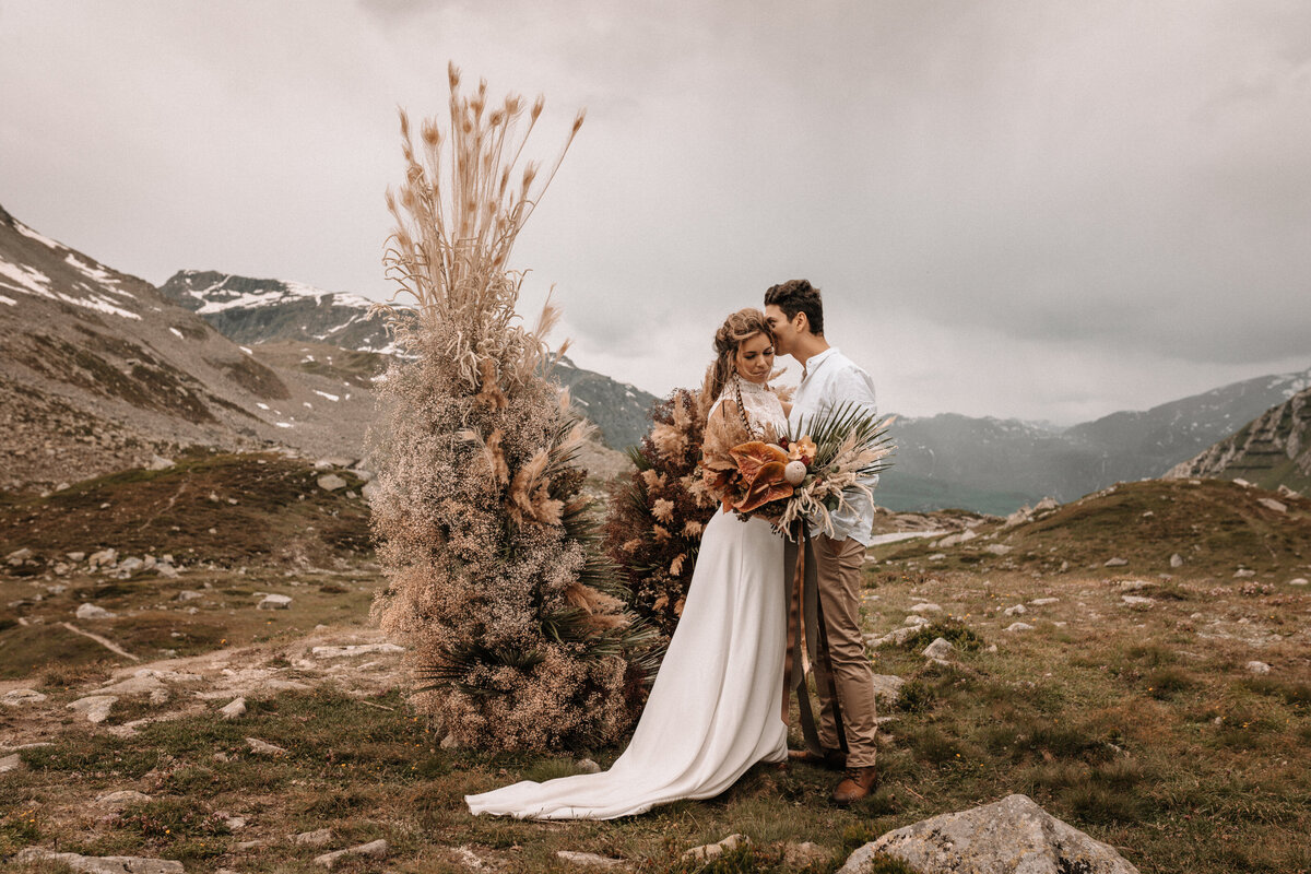 Brautpaar vor einem Traubogen in den Schweizer Bergen