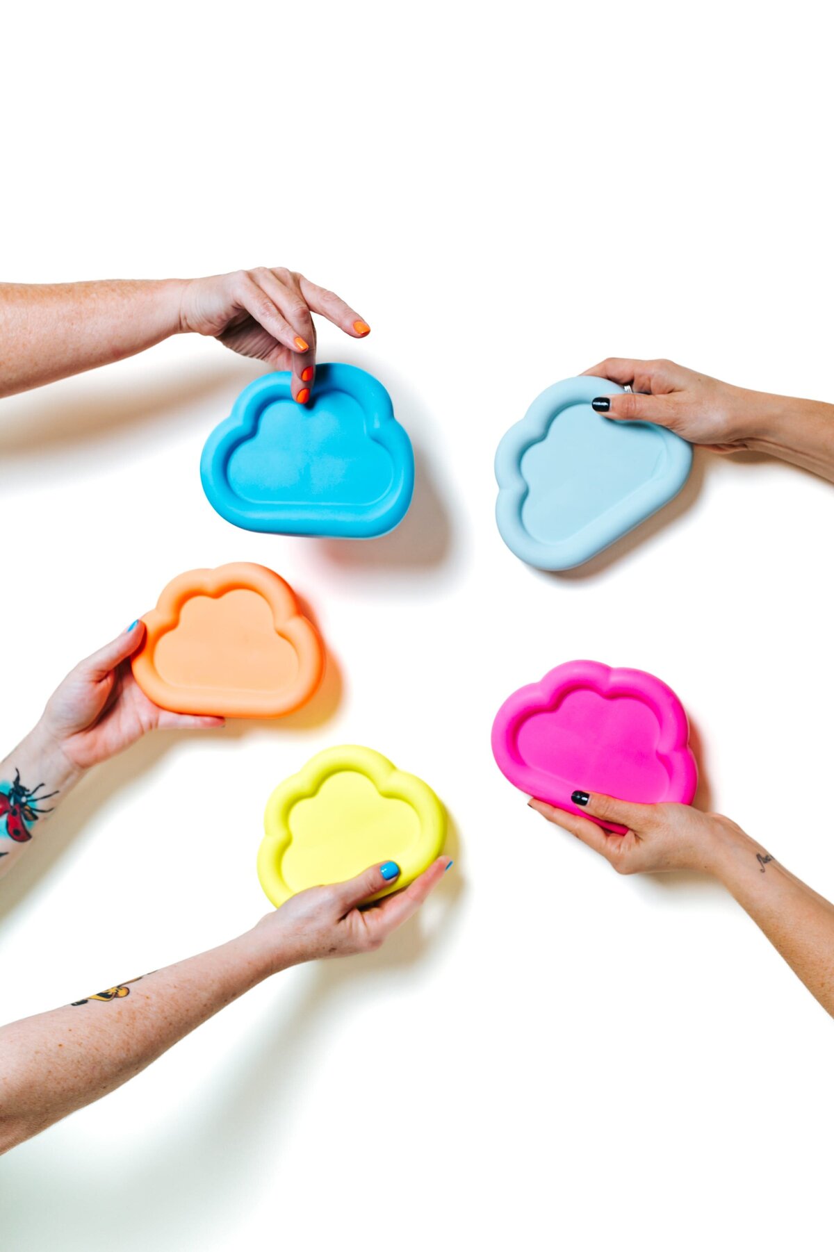 5 hands hold different colored cloud-shaped mold.
