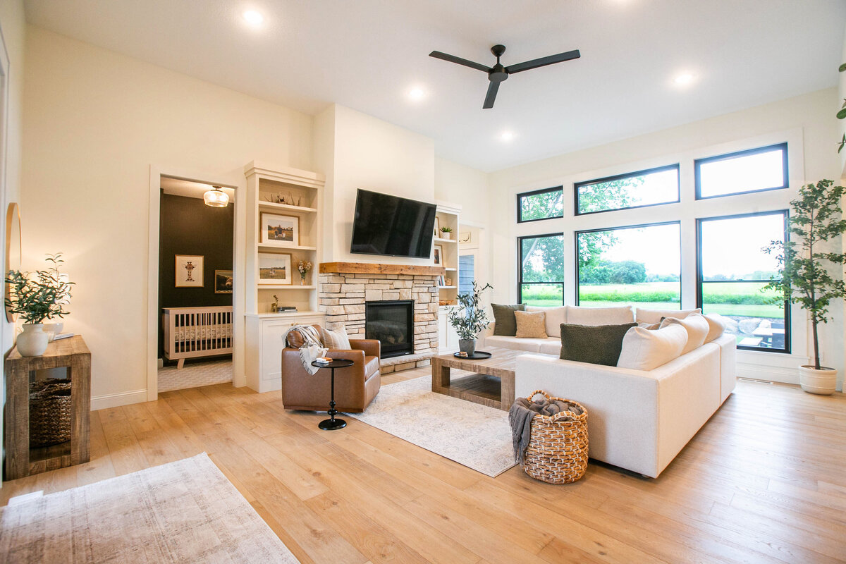 Cozy living room in Otsego custom home with fireplace, built-ins, and large windows