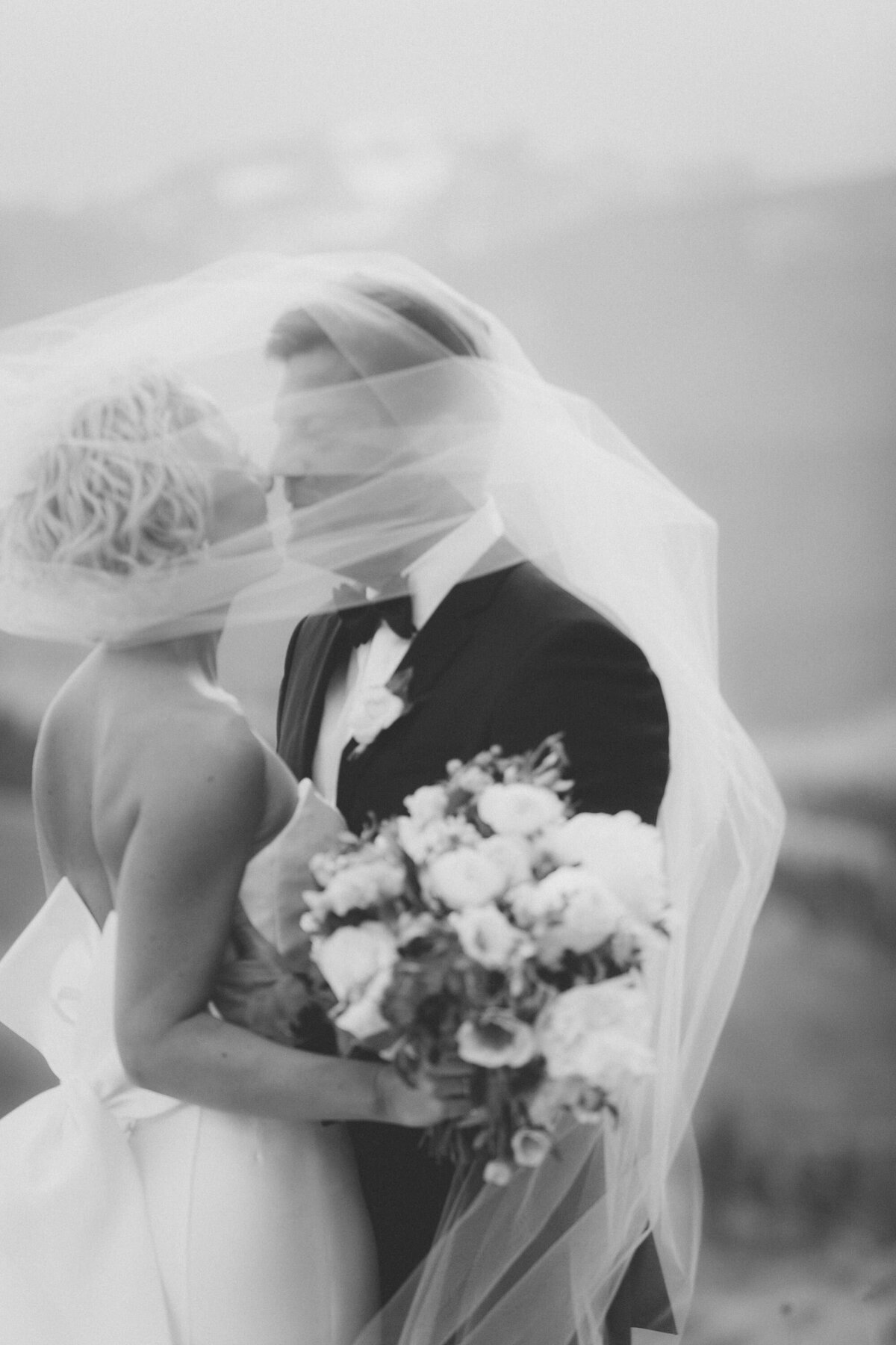 bride and groom kissing under veil