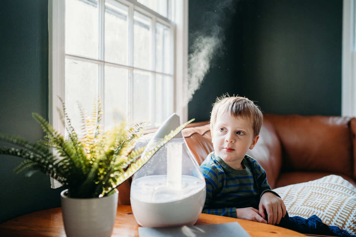 boy looks at steam coming out of humidifier