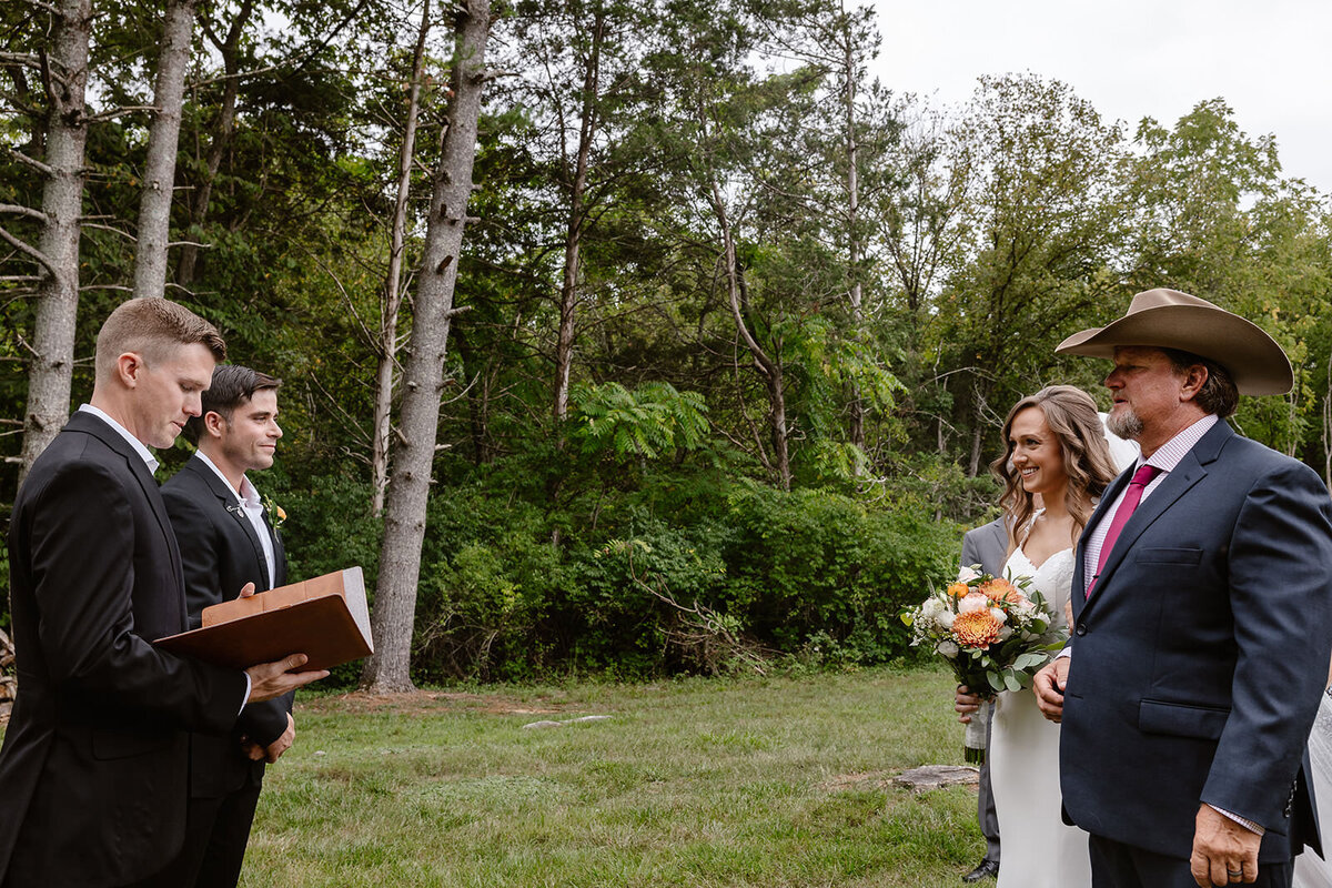 A person reading out of a book as a parent gives their child away during their wedding