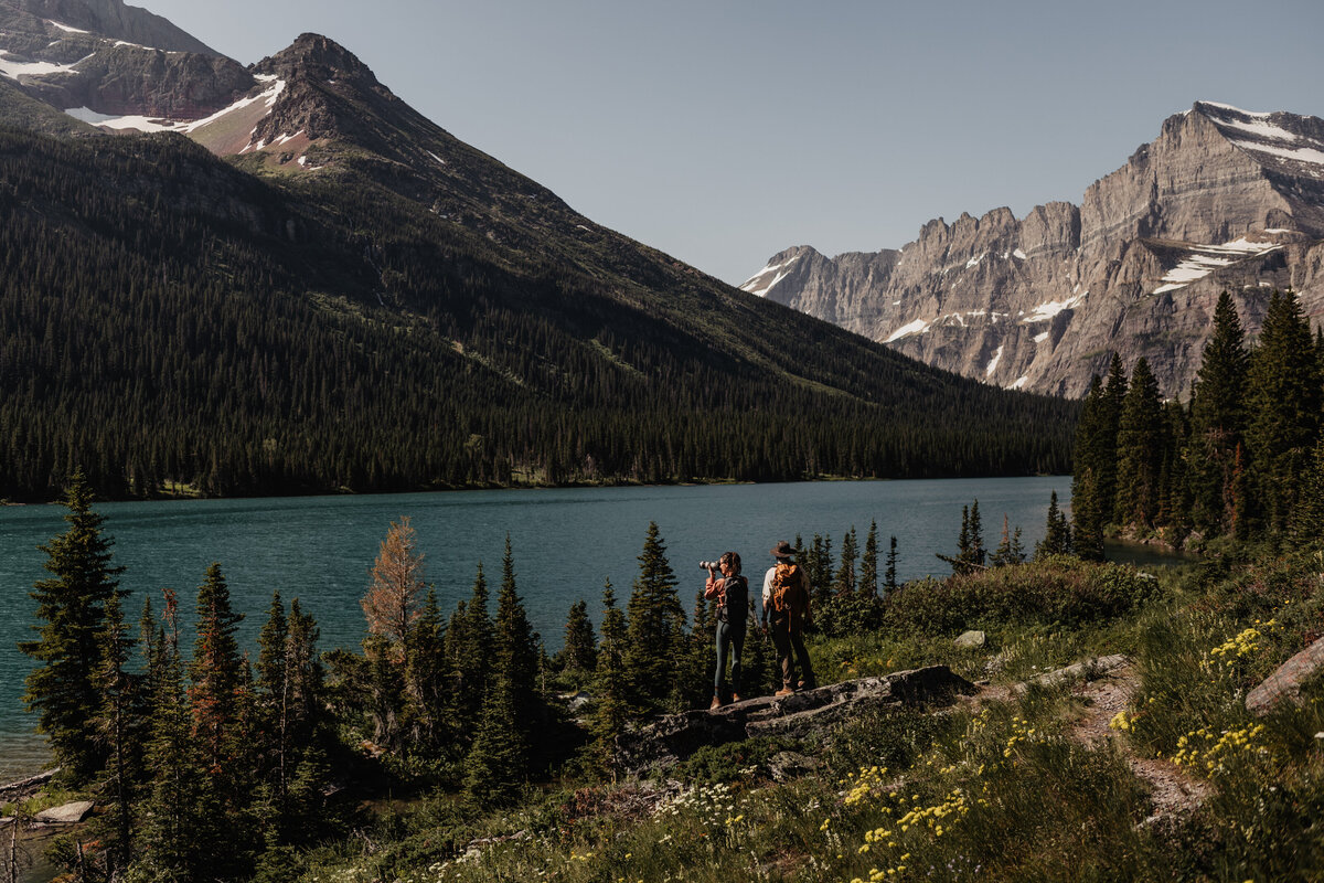 Montana elopement videographer and photographer standing in front of Lake Josephine in Glacier National Park