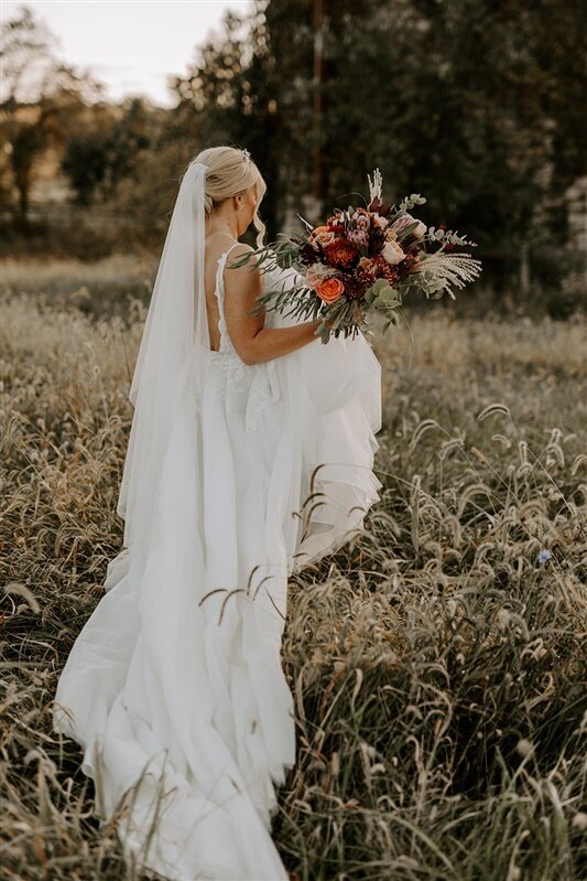 Bride with her autumn bouquet in the meadow