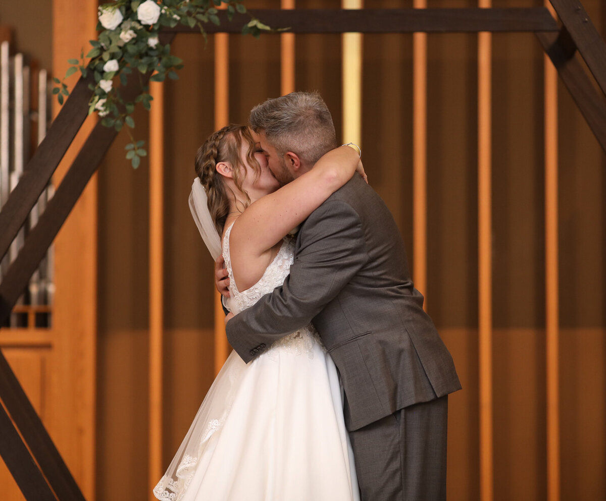 bride and groom sharing first kiss at Sojourn Church by Louisville wedding photographer Amanda Richardson Photography