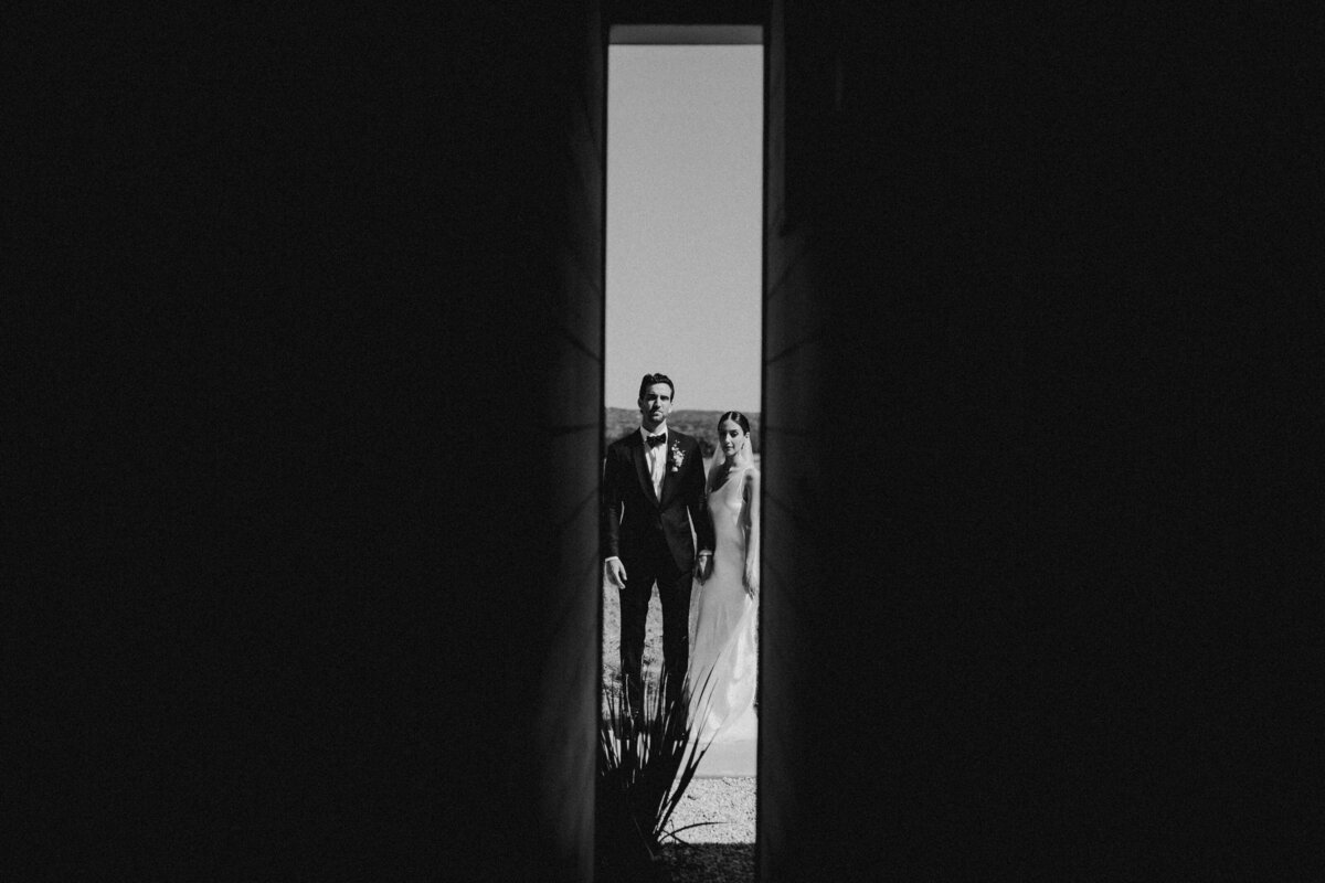Bride and groom appearing through a slit in the door