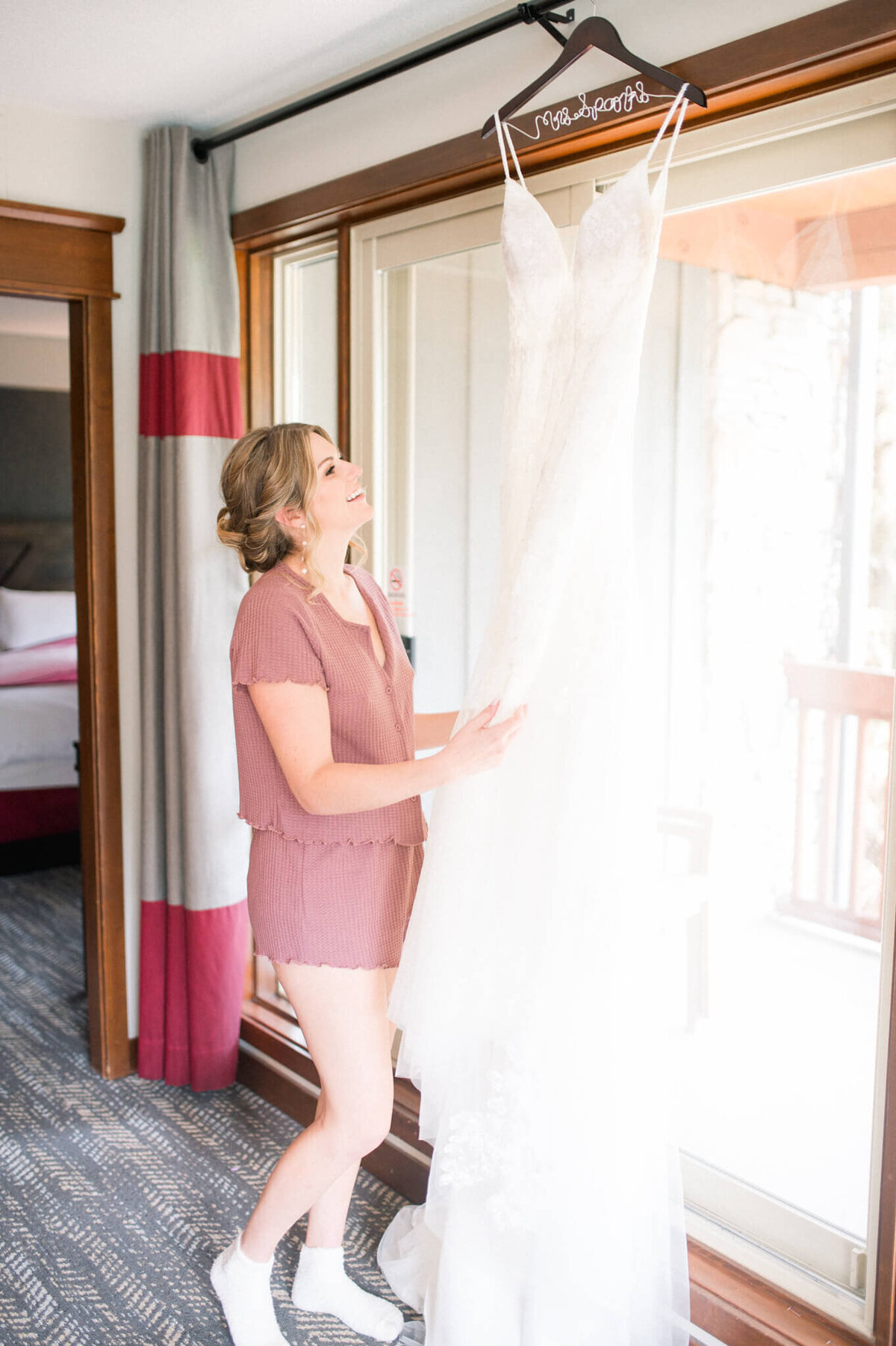 Bride looking at dress hanging in window captured by Toronto wedding photographer