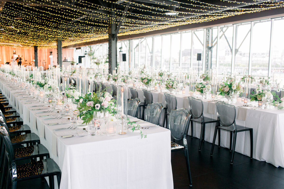 Tables at the Science Centre topped with lush floral arrangements under rows of suspended fairy lights.