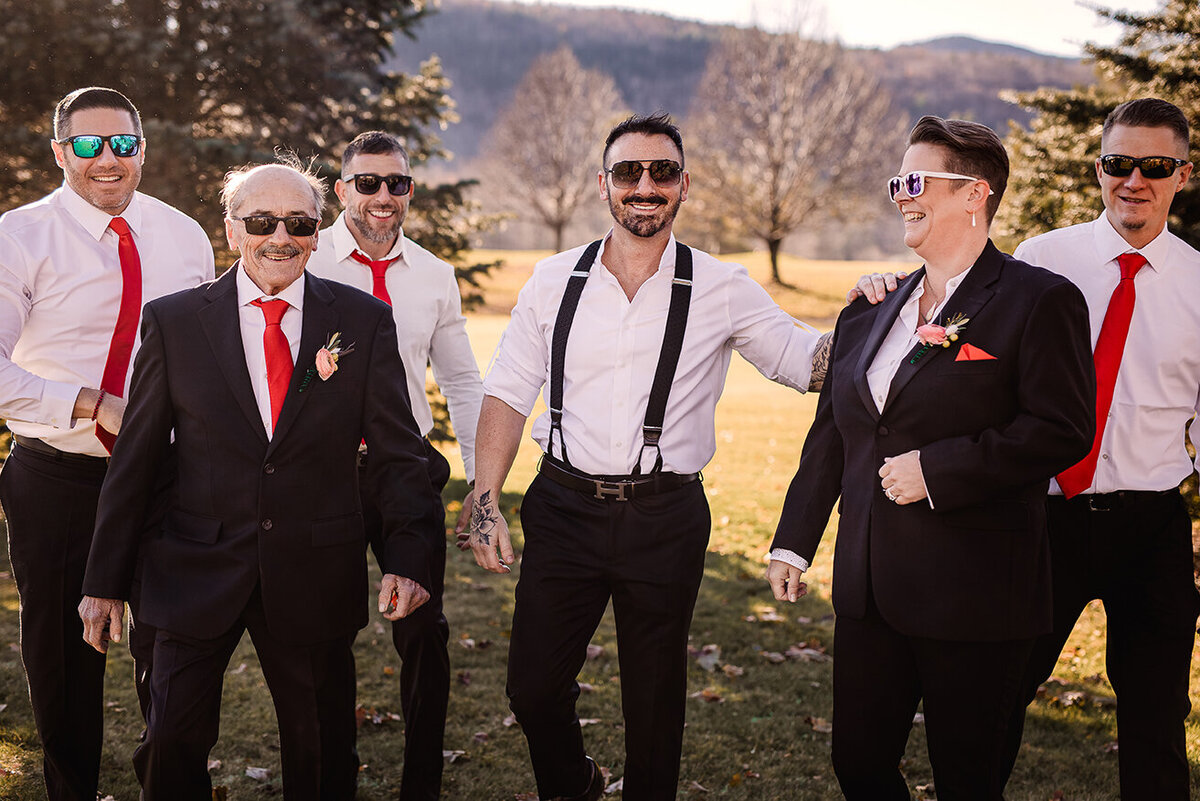 Groomsmen and groom walking in field on a sunny day wearing sunglasses at Wentworth Inn in Jackson NH Lisa Smith Photography