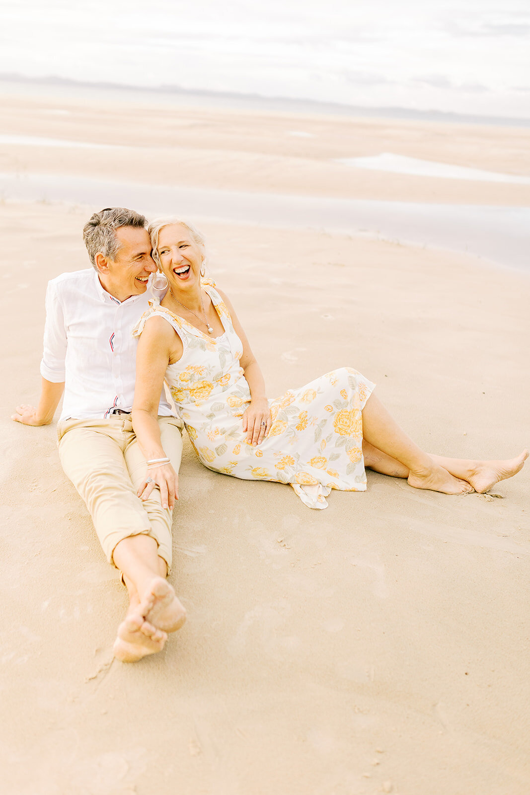 husband and wife laughing on beach
