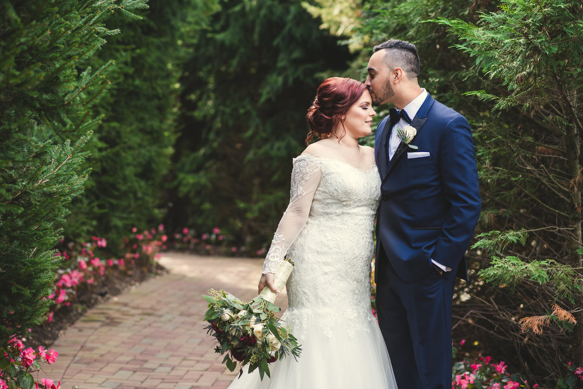 groom kissing bride forehead at Crest Hollow Country Club