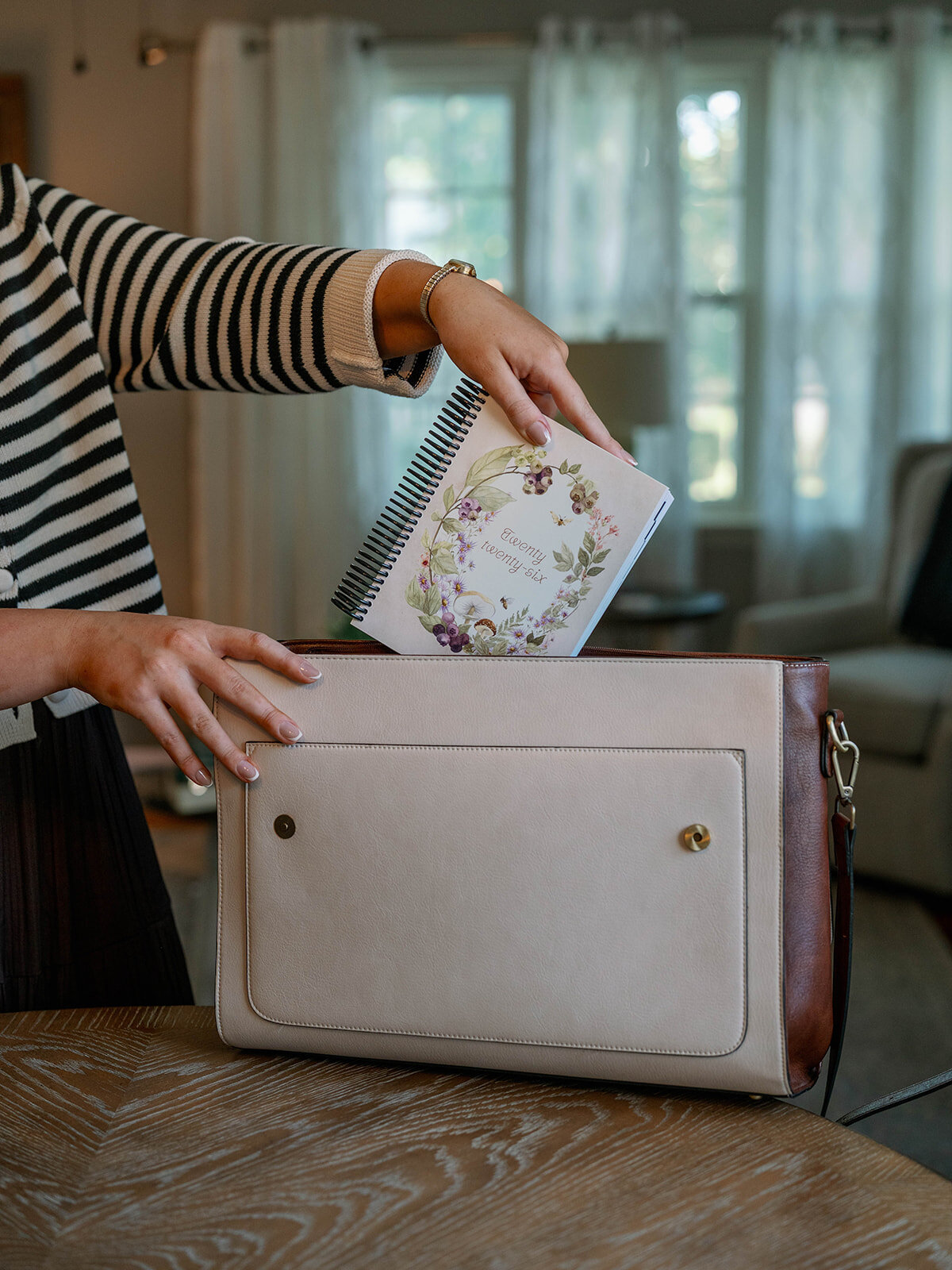 Woman placing a floral planner into a leather bag during the planner company branding session in Indiana.
