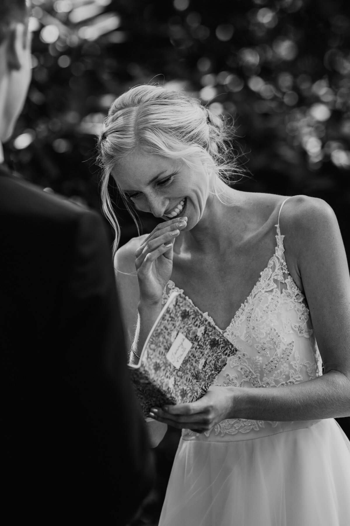 Bride wiping tears while holding vow book