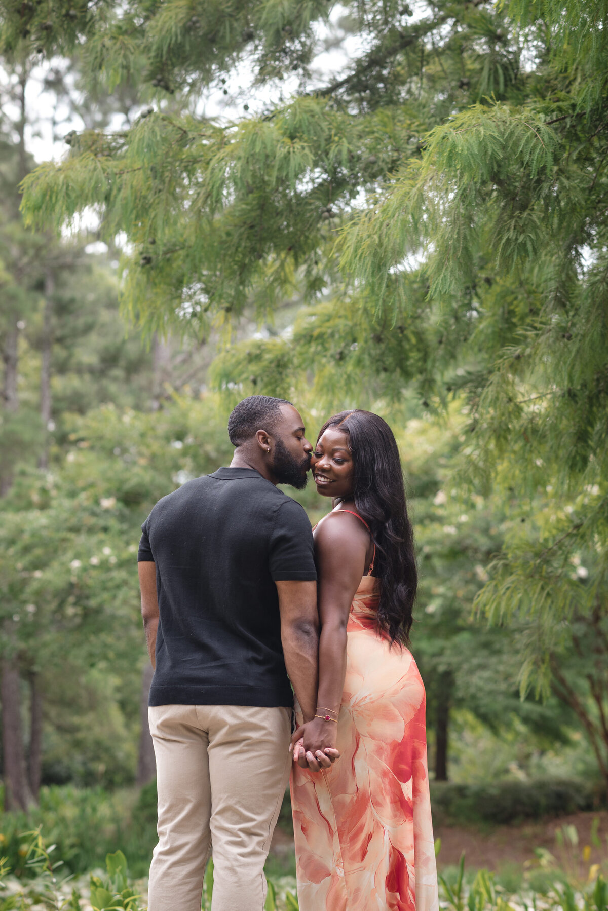 Man kisses his fiancée's cheek after a romantic outdoor proposal at Glencairn Gardens, Rock Hill SC, by Charlotte engagement and proposal photographer DeLong Photography.