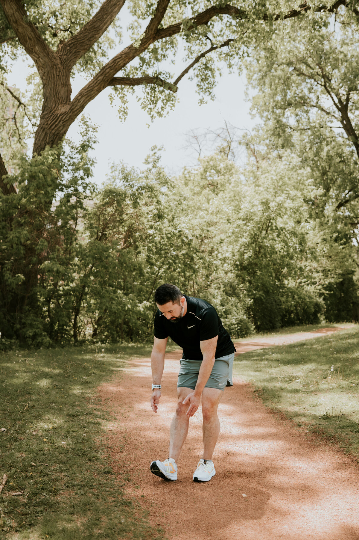 Candid dating profile photo of a man tying his running shoes outdoors in Minneapolis, ideal for showcasing an athletic, approachable vibe on dating apps.