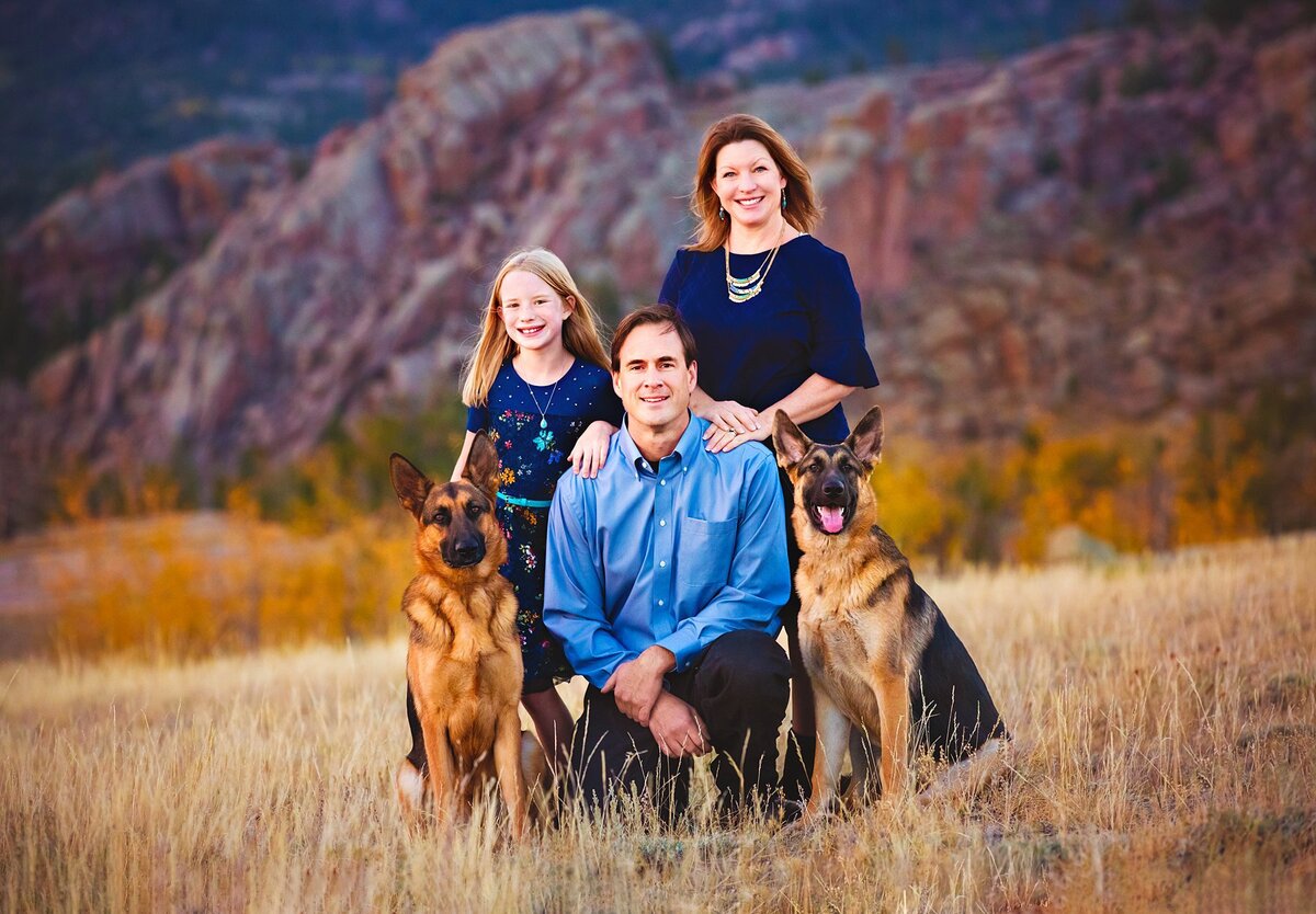 Incredible fall photo in the mountains of a family in the Vedauwoo mountains with their dogs.