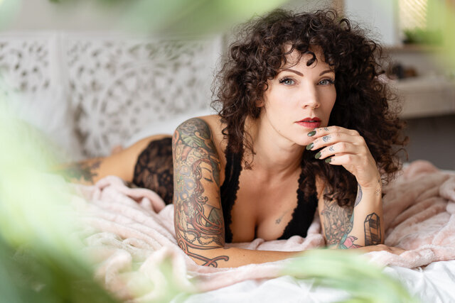 tattooed woman in black lace lingerie on bed