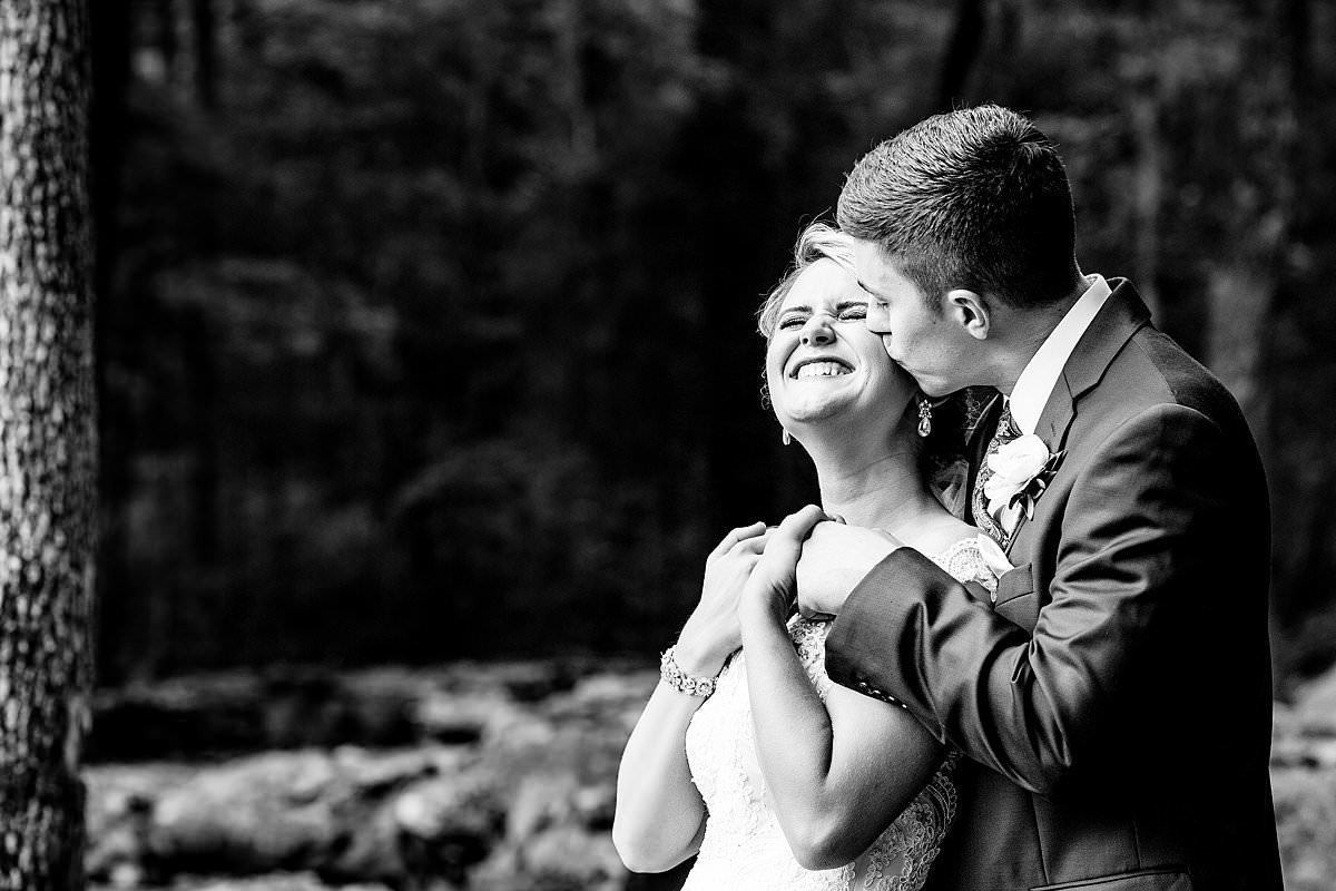 Black and white photo of groom kissing bride on cheek