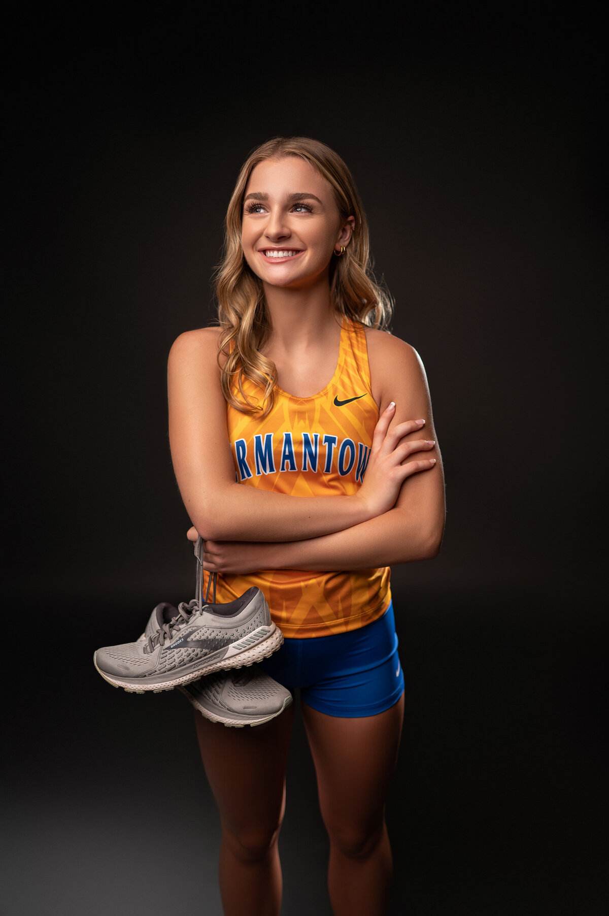 A girl from Germantown High School poses for her senior pictures wearing her track uniform in our Waukesha photo studio.