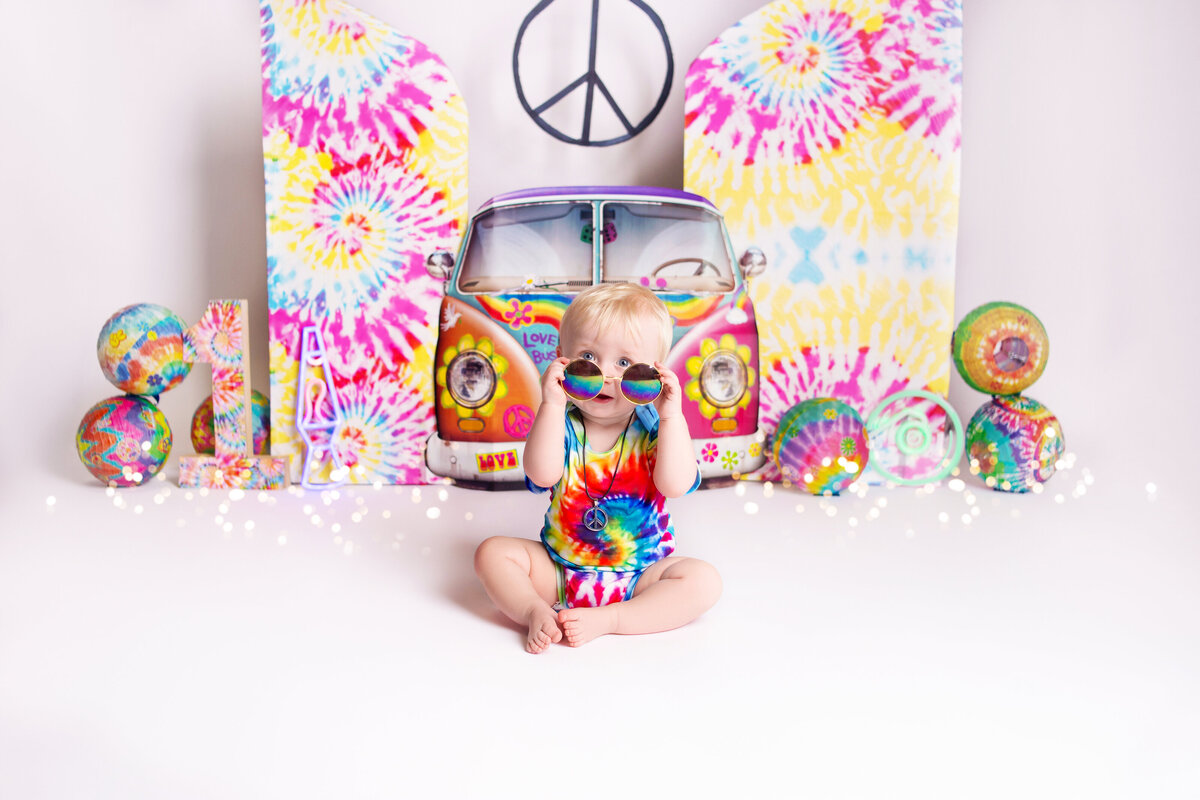 Baby boy wearing tye dye during cake smash photoshoot with Nashville, TN photographer