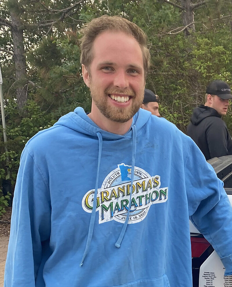 Before image of client wearing a blue marathon sweatshirt, smiling casually outdoors before his professional dating photography session in Minneapolis–St. Paul.
