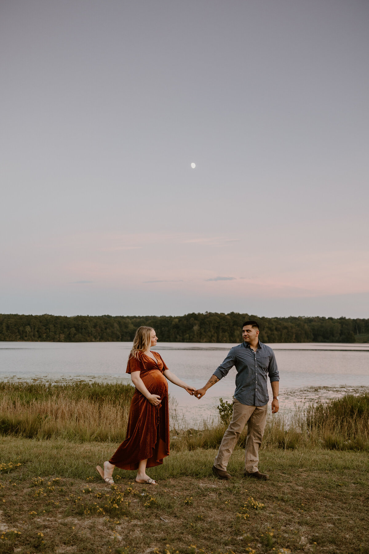 Expecting couple walking together by the lake a twighlight.
