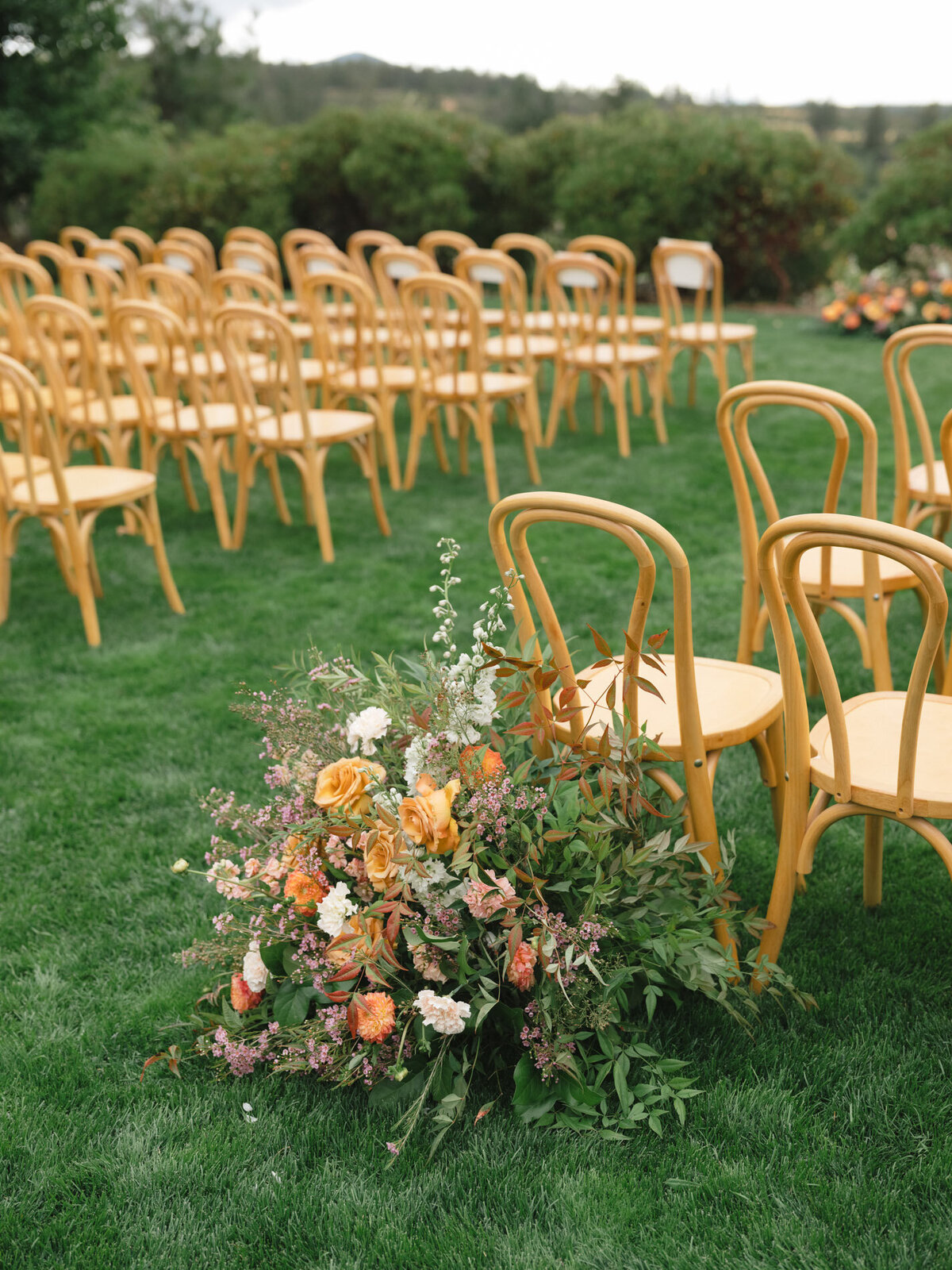 modern wood chairs for a wedding ceremony aisle with florals representing full service design and calligraphy by Life in Letters.