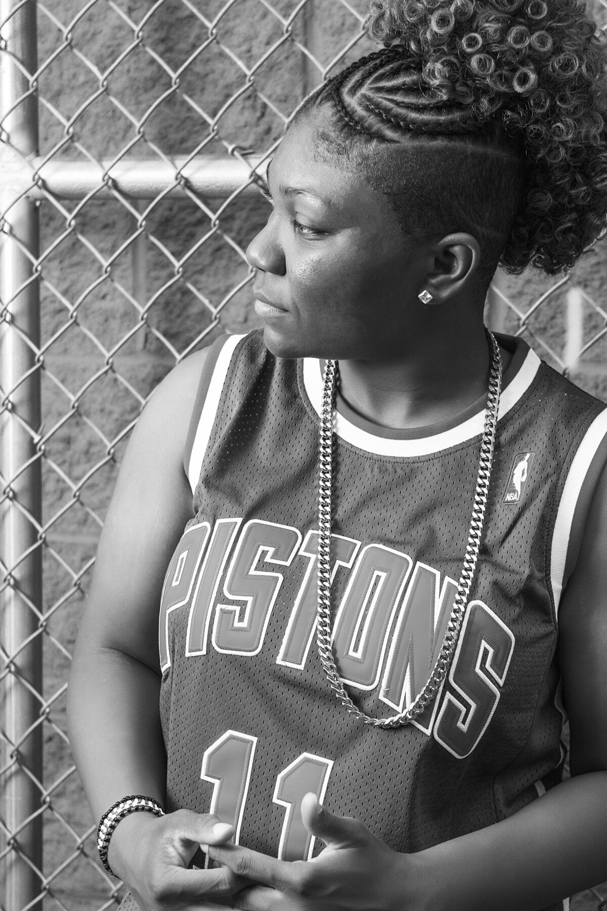 Woman in Detroit Pistons jersey standing in front of a fence