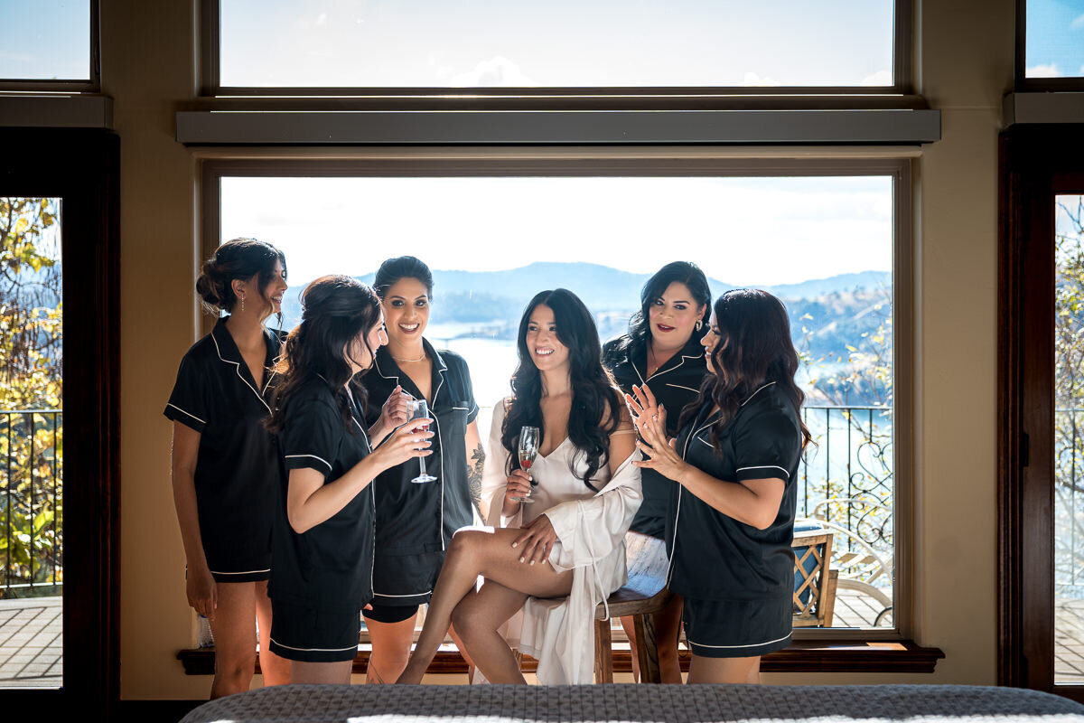 A joyful moment captured as the bride and her bridesmaids relax in matching robes in the bridal suite at Airola Road Vineyards, surrounded by serene vineyard views and wedding day excitement.