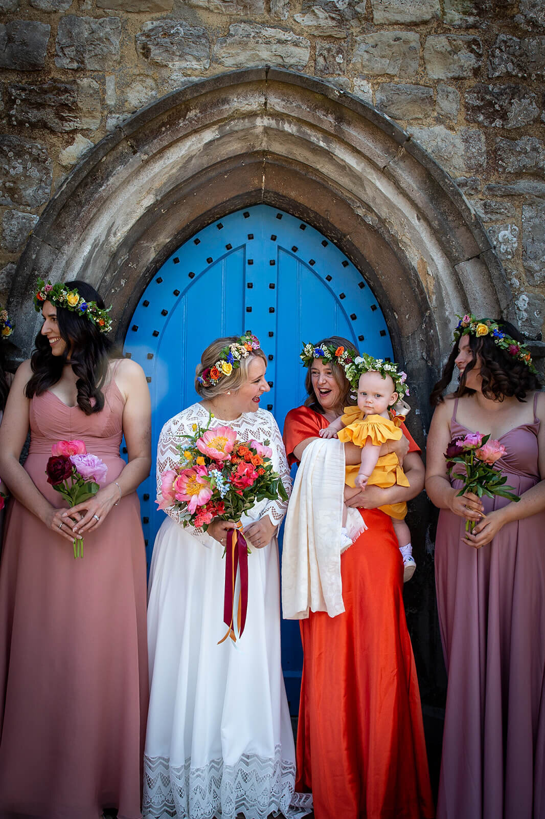 Bride and bridal party smiling to baby outside Kent church
