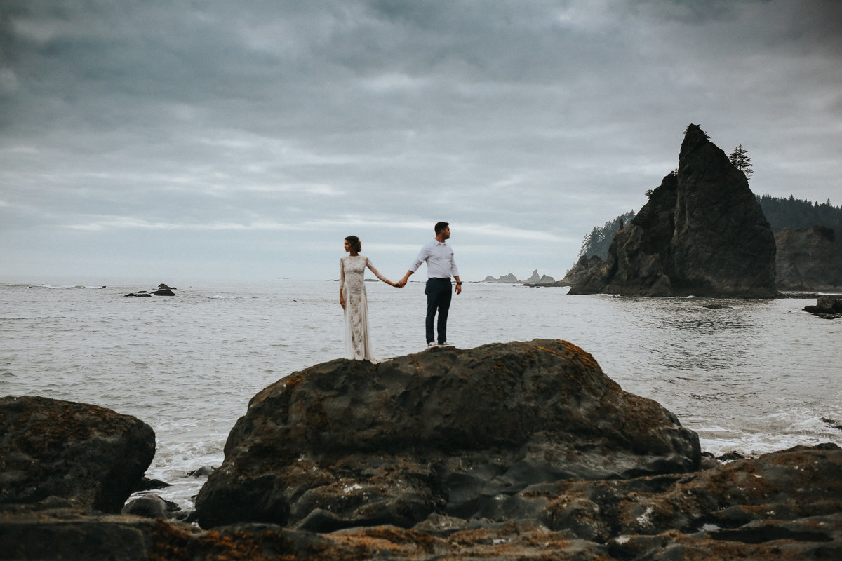 Bride and groom on rocks of La Push Washington in the middle of the Washington coast.