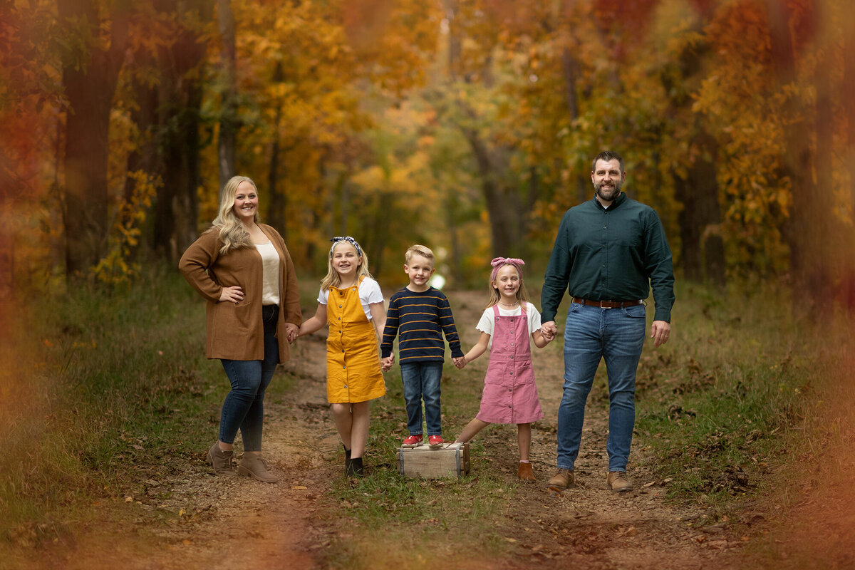 Whole family holds hands and stand on a path in forest
