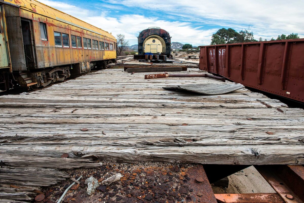 Rust and wooden boards deteriorate with old train cars on the right and left side