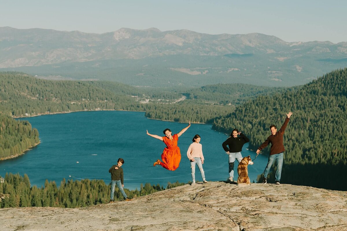 donner fall family session of them jumping up with lake donner behind them
