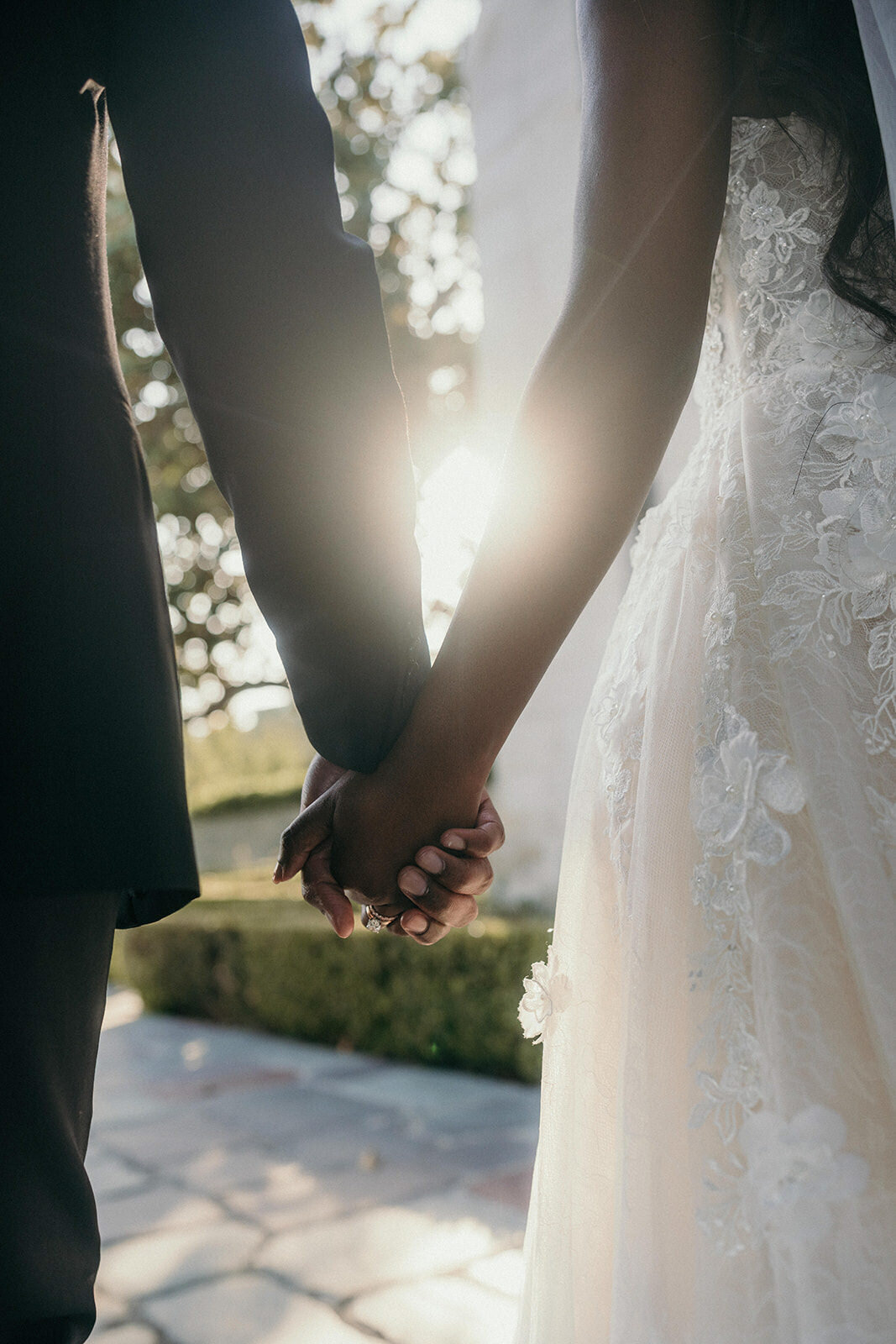 Bride and groom hold hands in the sunlight.