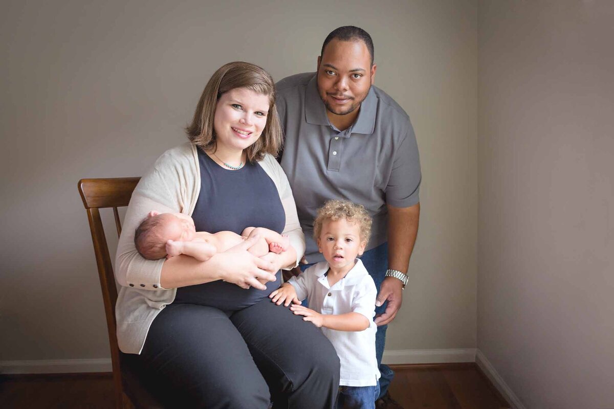 Family of four with mom holding newborn baby during an in home session in Columbia, SC