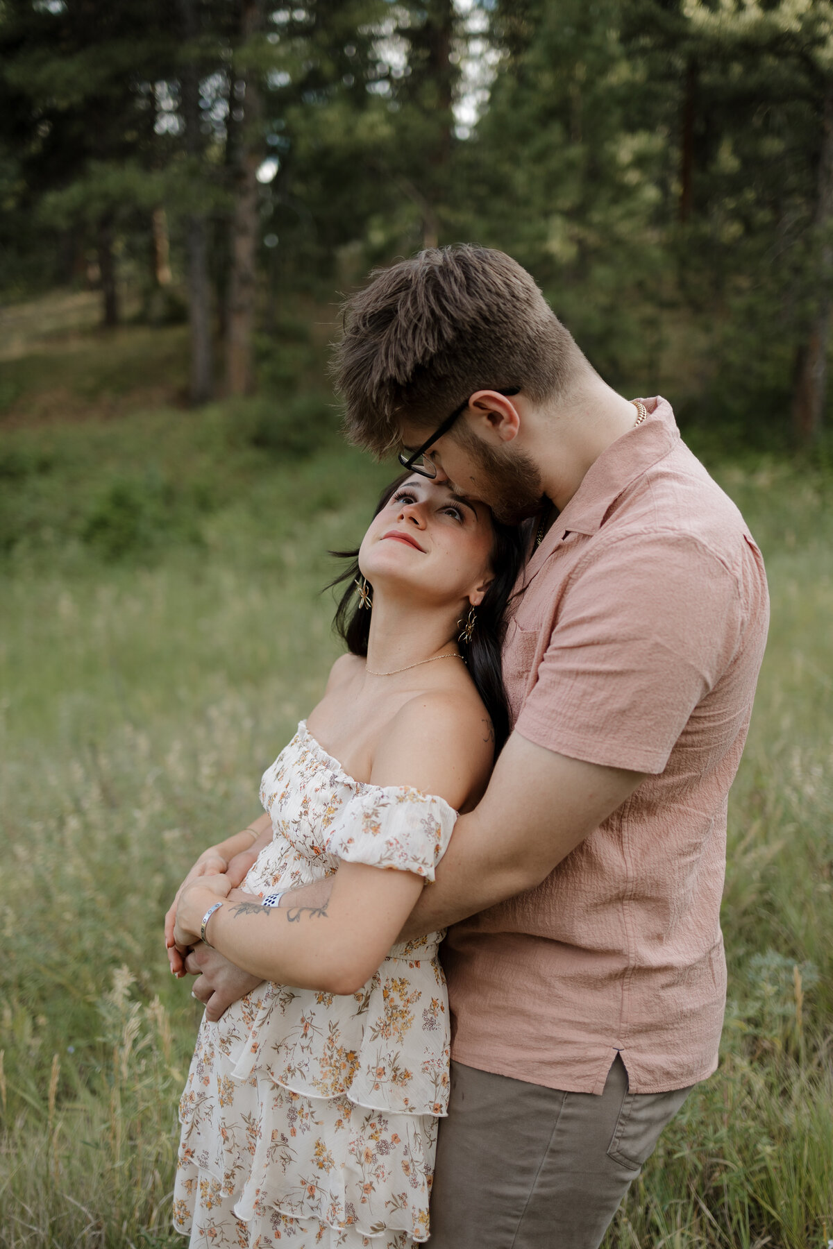 Boy kissing girls forehead while hugging her belly with their baby in it in Boulder Colorado