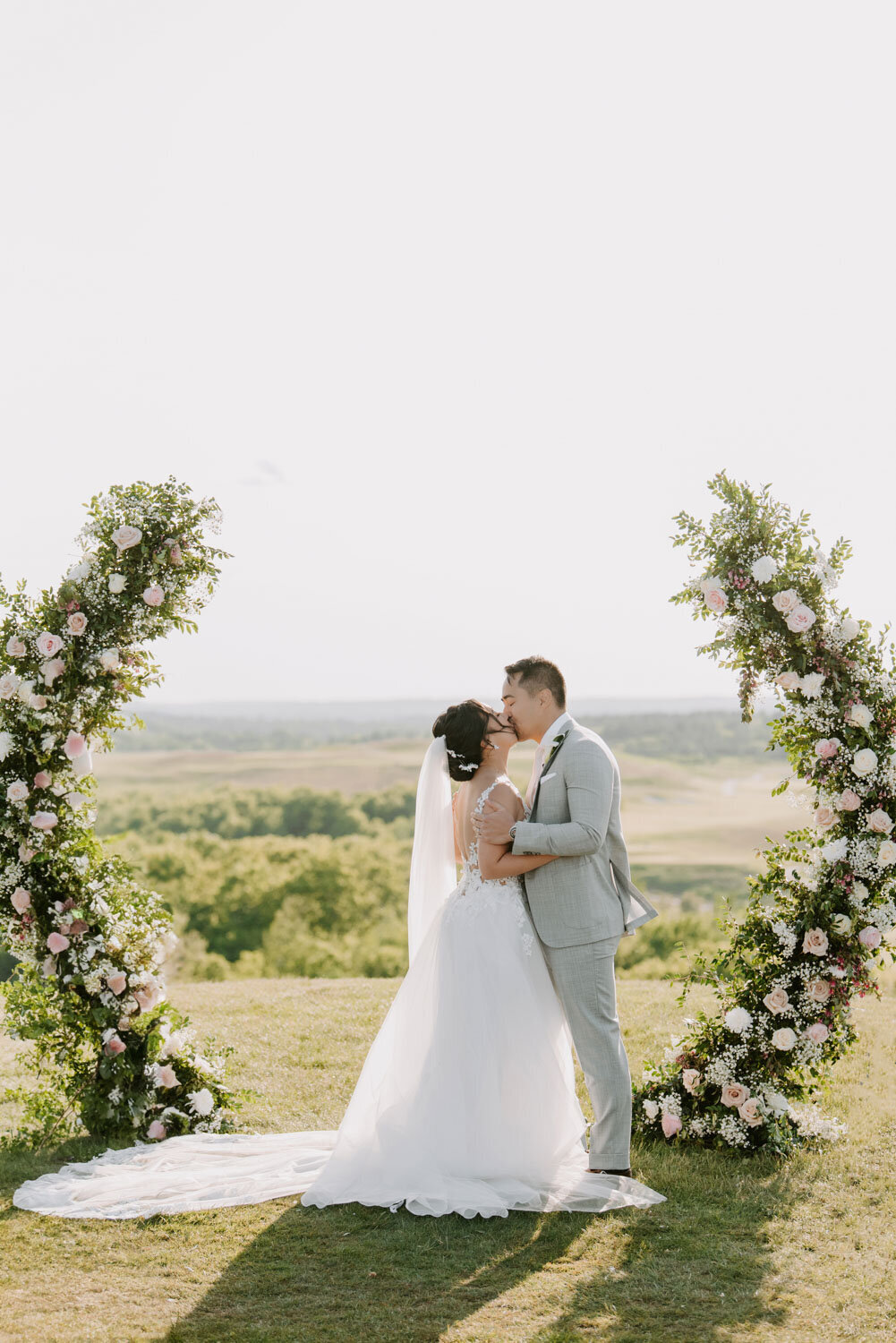 Outdoor wedding ceremony with bride and groom under a floral arch