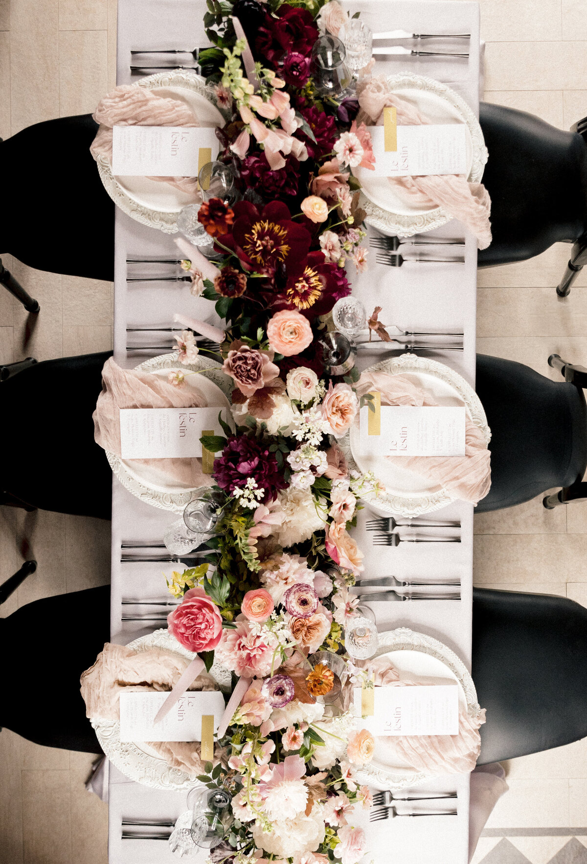 Bird’s eye view of a floral centrepiece of red and pink flowers at a Chateau St Agnes wedding reception.