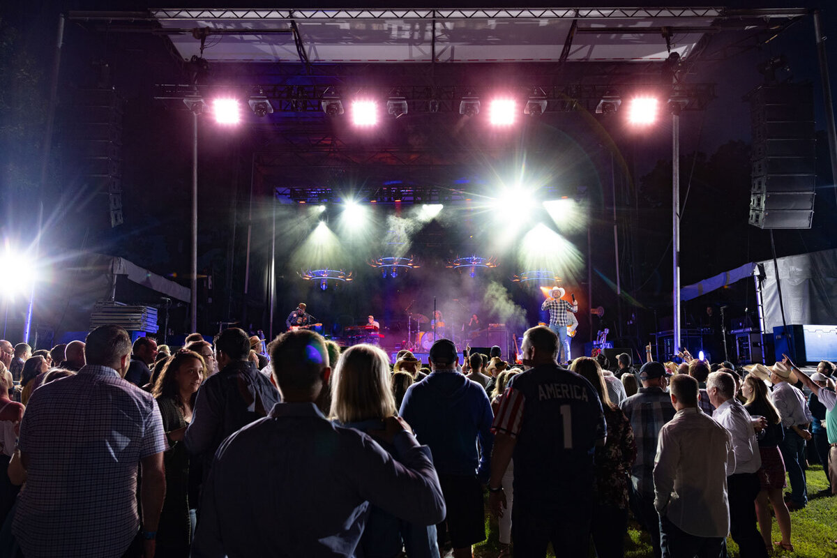 Outdoor concert with bright stage lights and large audience