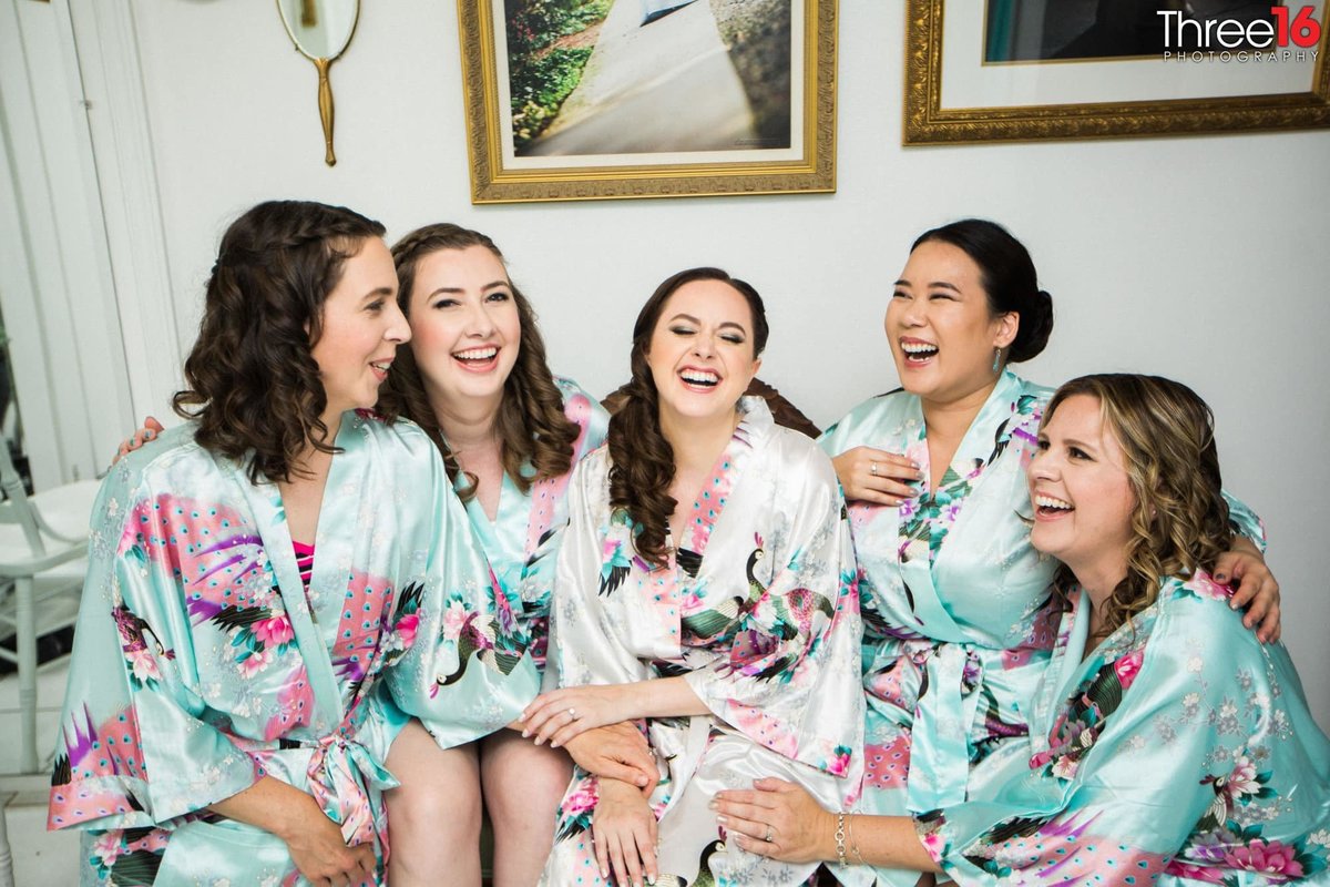 Bride and Bridesmaids laugh together while in their robes
