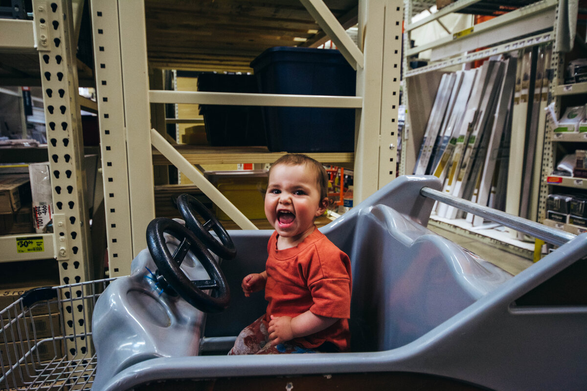 A little girl sits ina  shopping cart at Home Depot