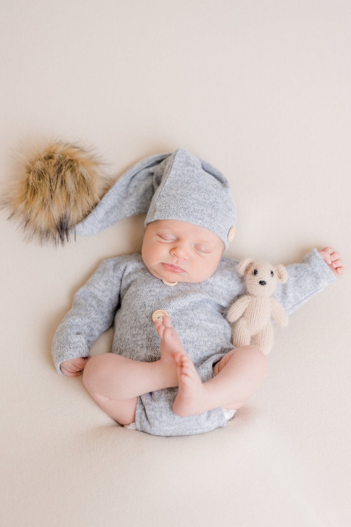 newborn boy in pompom hat with teddy